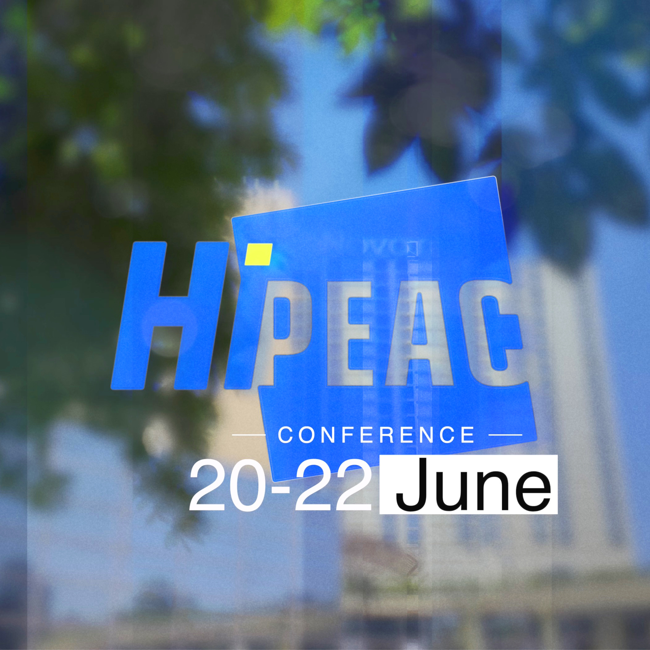hipeac-conference-budapest-event-film Logo mit dem Park vor dem Novotel Hotel im Hintergrund